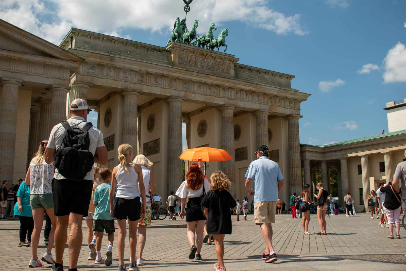 A group of people walking in front of the brandenburg gate on an exclusive tour of Berlin
